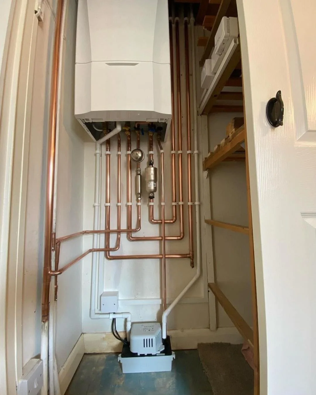 Completed boiler and copper pipe installation inside a cupboard by DPB