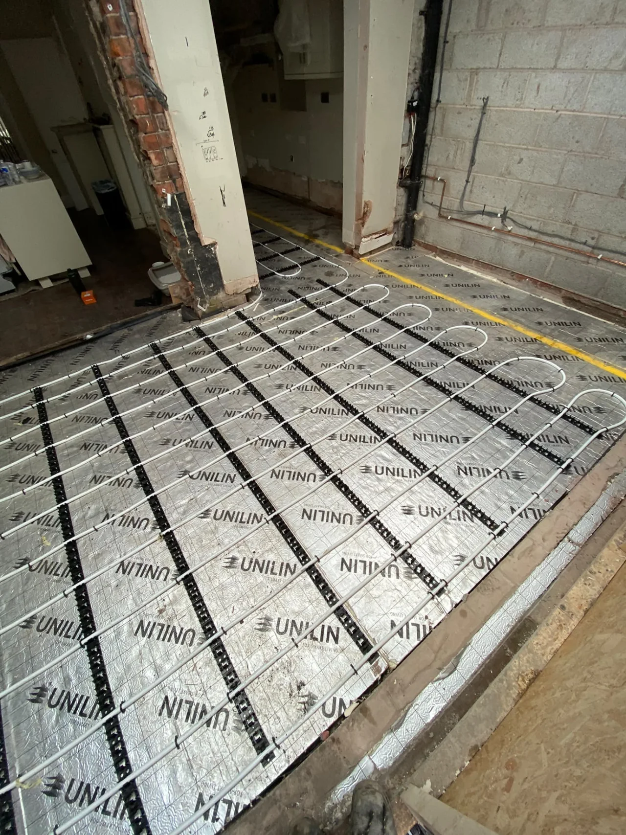 Underfloor heating pipes secured over insulation during installation by DPB